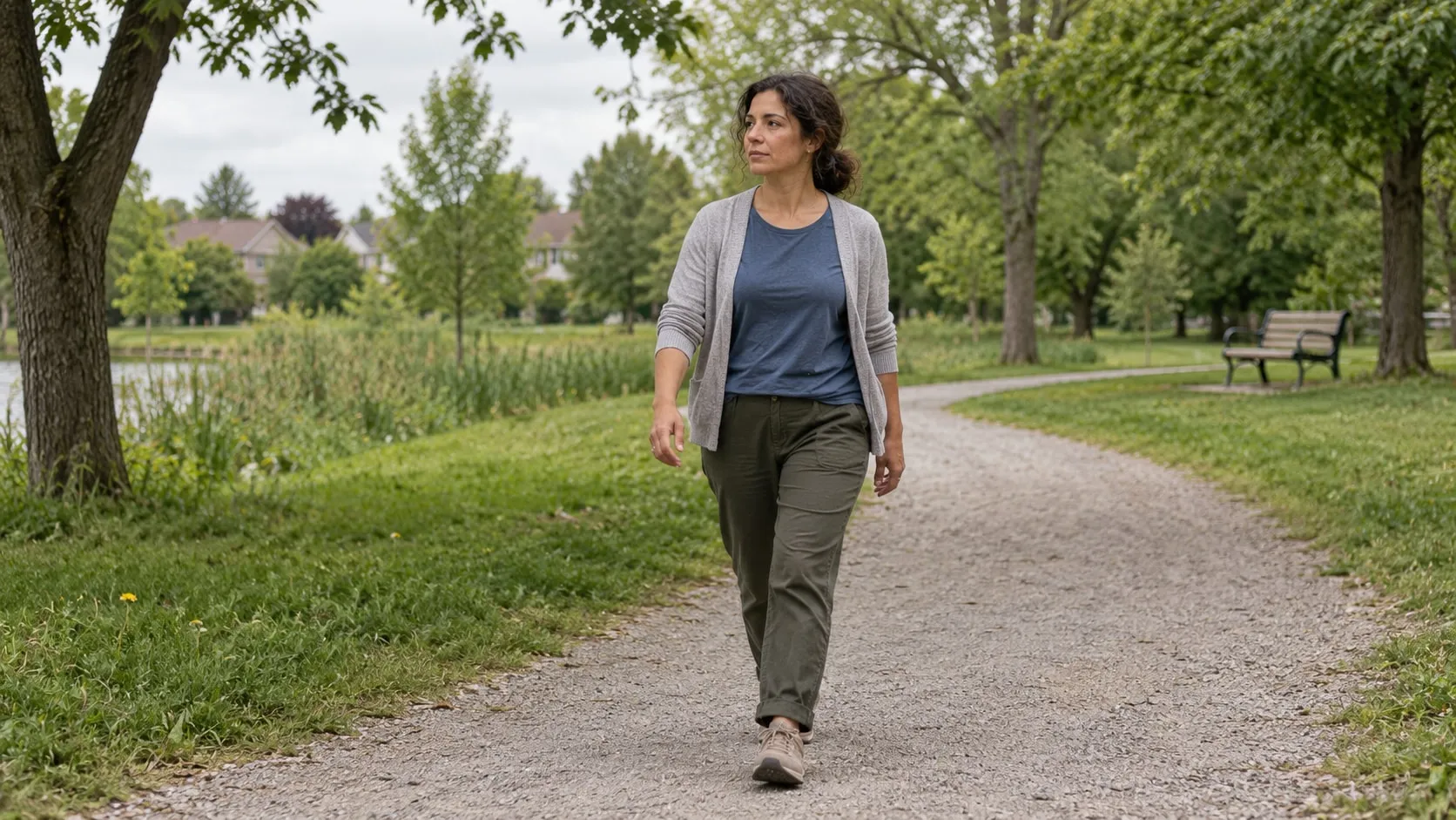 A woman walks alone along a path through a neighbourhood park.